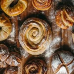 A beautifully styled flat-lay image of various rising doughs, including sourdough, cinnamon rolls, and artisan bread, with warm natural lighting.